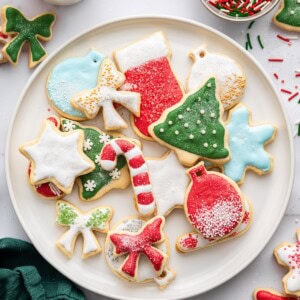 A plate filled with decorated holiday sugar cookies—trees, bows, snowflakes, ornaments, and candy canes.