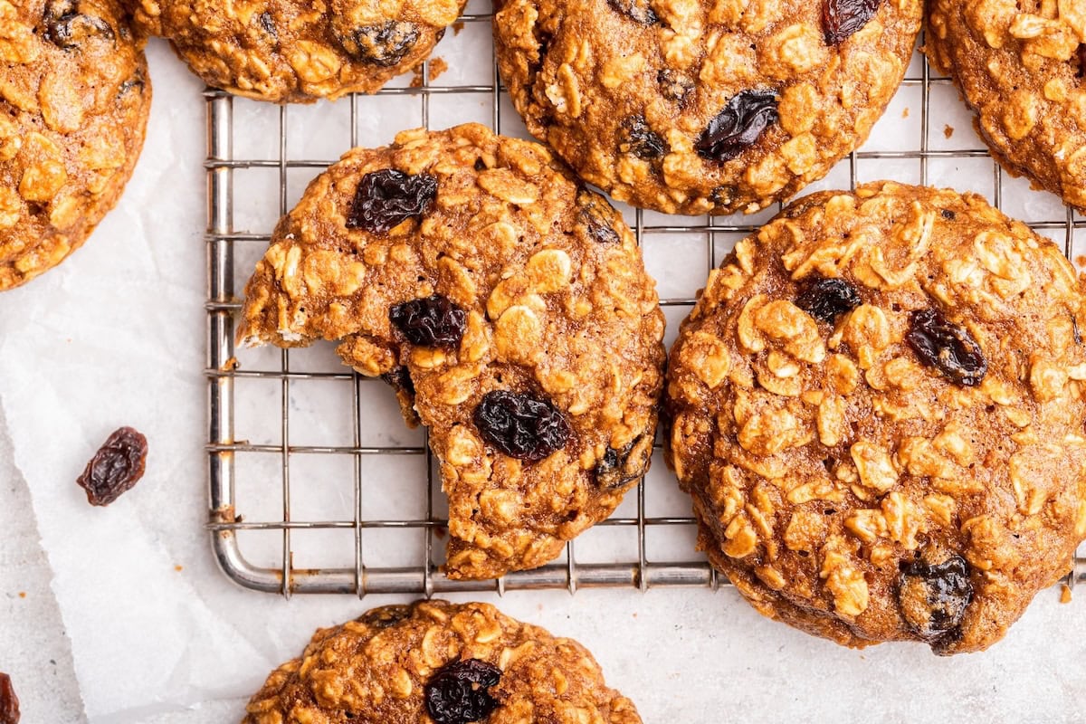 Oatmeal raisin cookies on a cooling rack with one cookie having a bite taken from it.