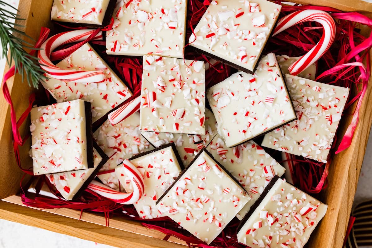 Square peppermint bark pieces stacked on top of each other in a gift box.