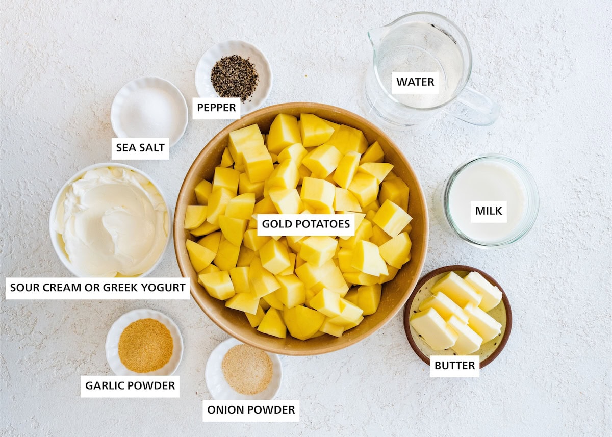 Ingredients measured out to make Slow Cooker Mashed Potatoes: water, milk, butter, gold potatoes, pepper, onion powder, sea salt, garlic powder and sour cream.