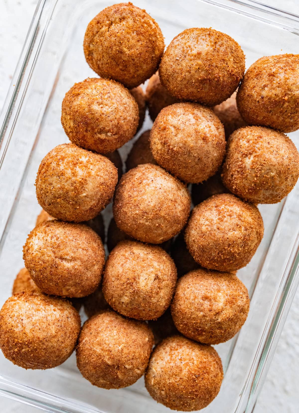Snickerdoodle protein ball recipe Snickerdoodle protein balls packed in a glass container, showing their cinnamon sugar coating.