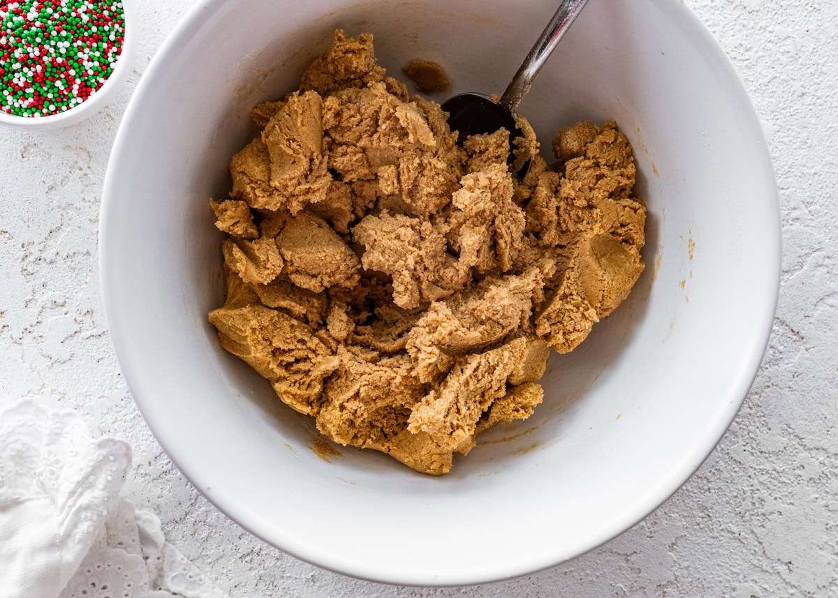 sugar cookie protein ball dough A white mixing bowl filled with thick sugar cookie protein ball dough, ready to be rolled into balls.