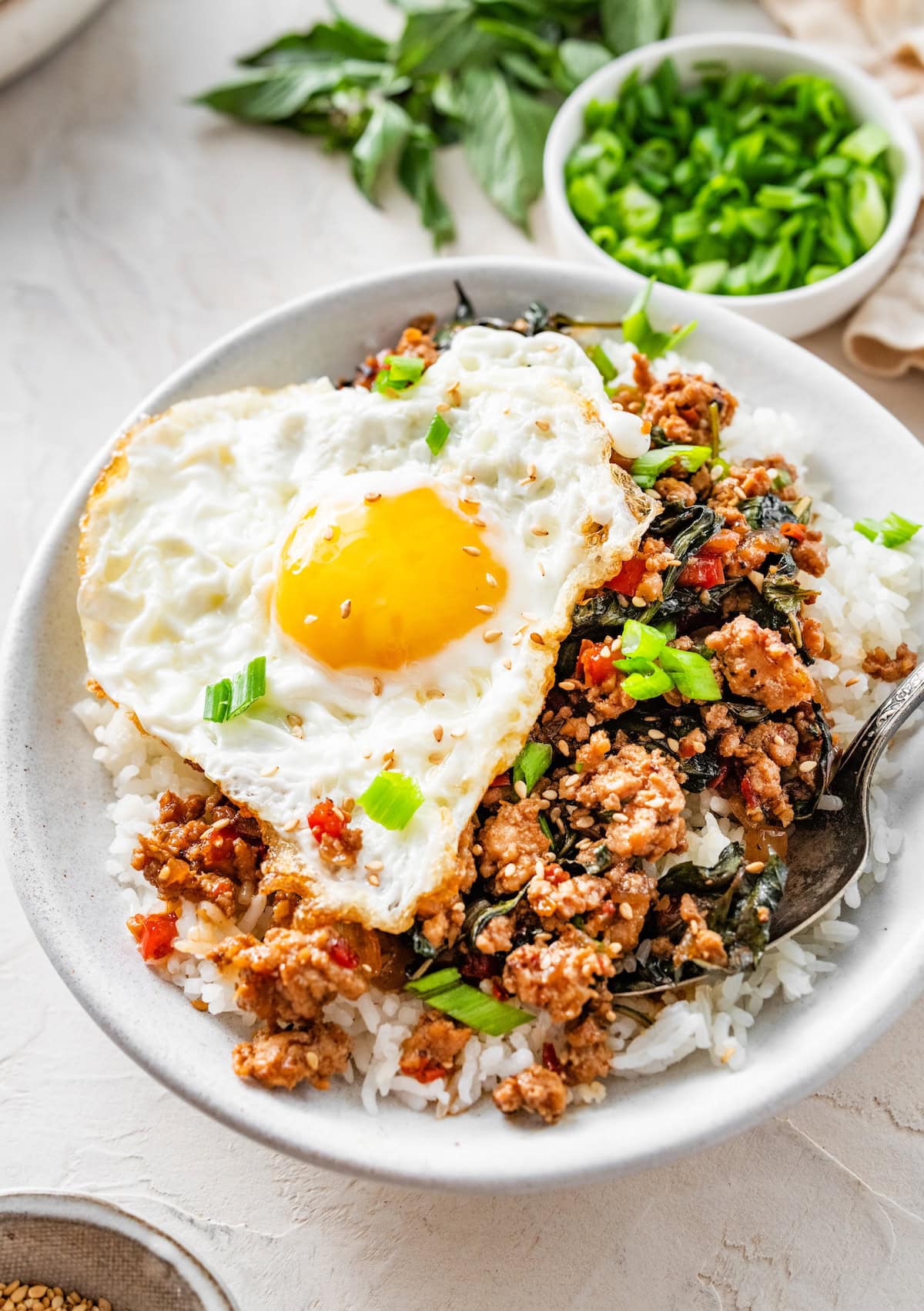 Thai basil chicken bowl with egg Thai basil chicken bowl topped with a fried egg and sliced green onions.
