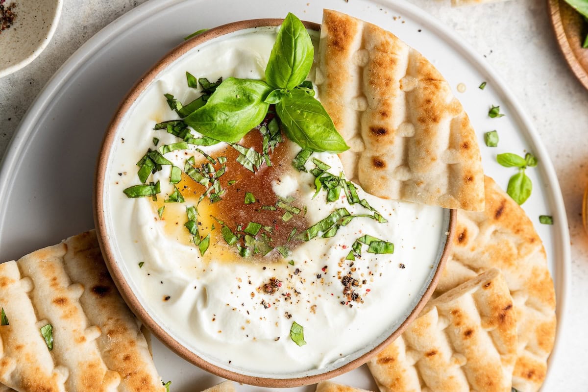 A triangle of pita dipped into a whipped feta dip.