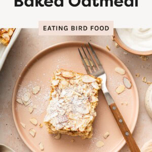 Slice of almond croissant baked oatmeal topped with powdered sugar and sliced almonds on a plate.