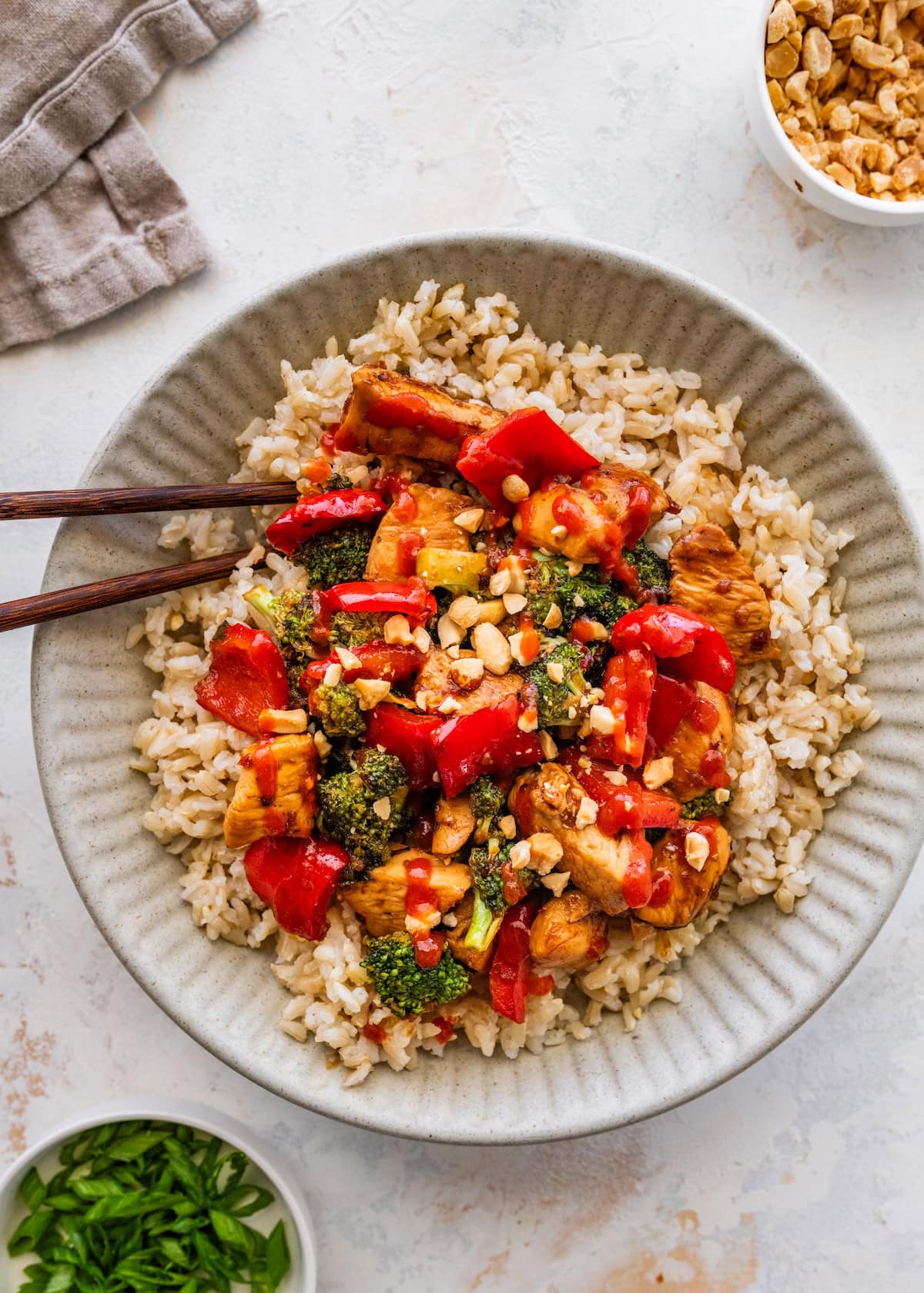 Healthy kung pao chicken brown rice Healthy kung pao chicken served over brown rice in a shallow bowl.