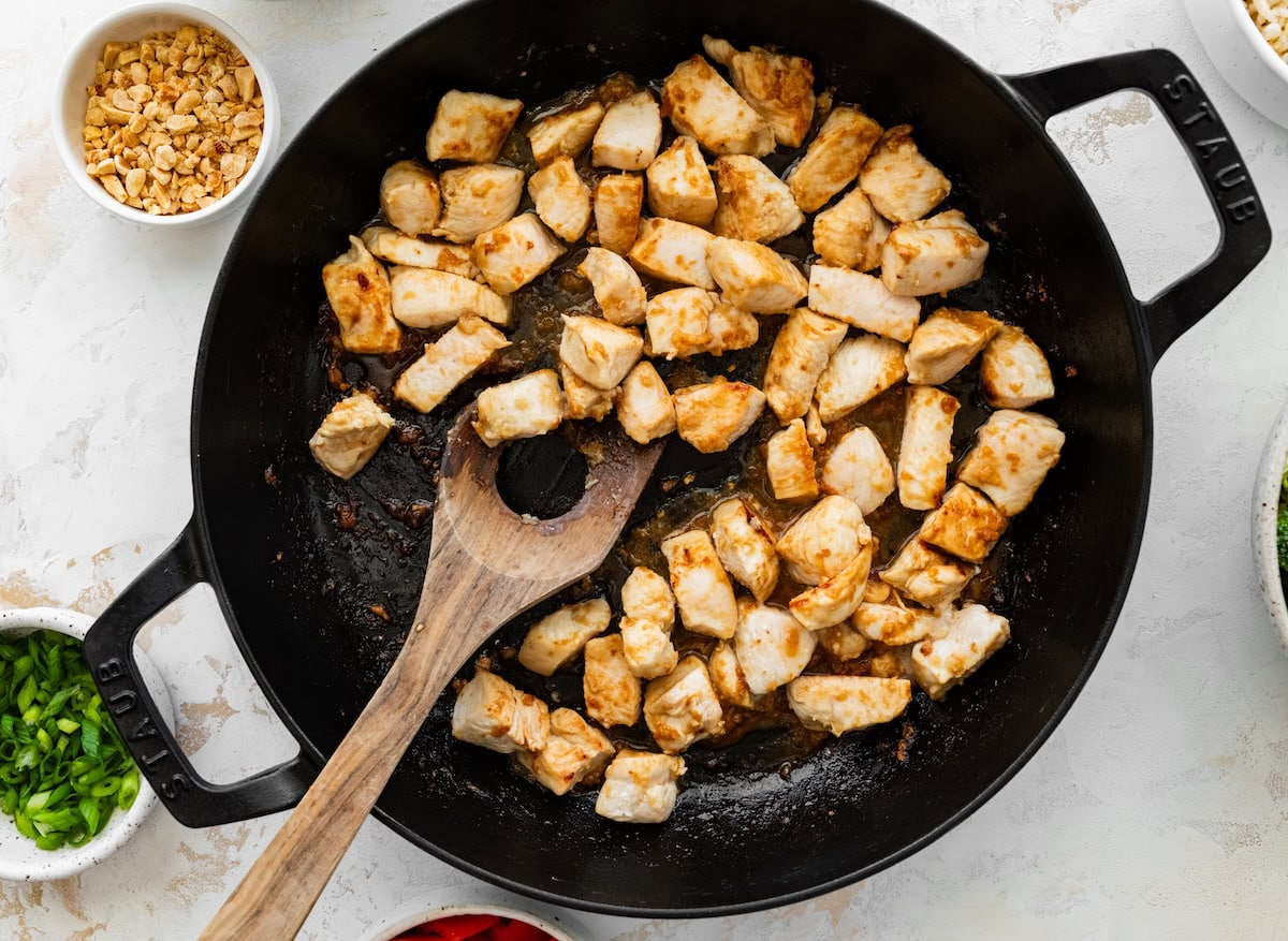 Diced chicken breast Diced chicken breast cooking in a skillet until golden and cooked through.