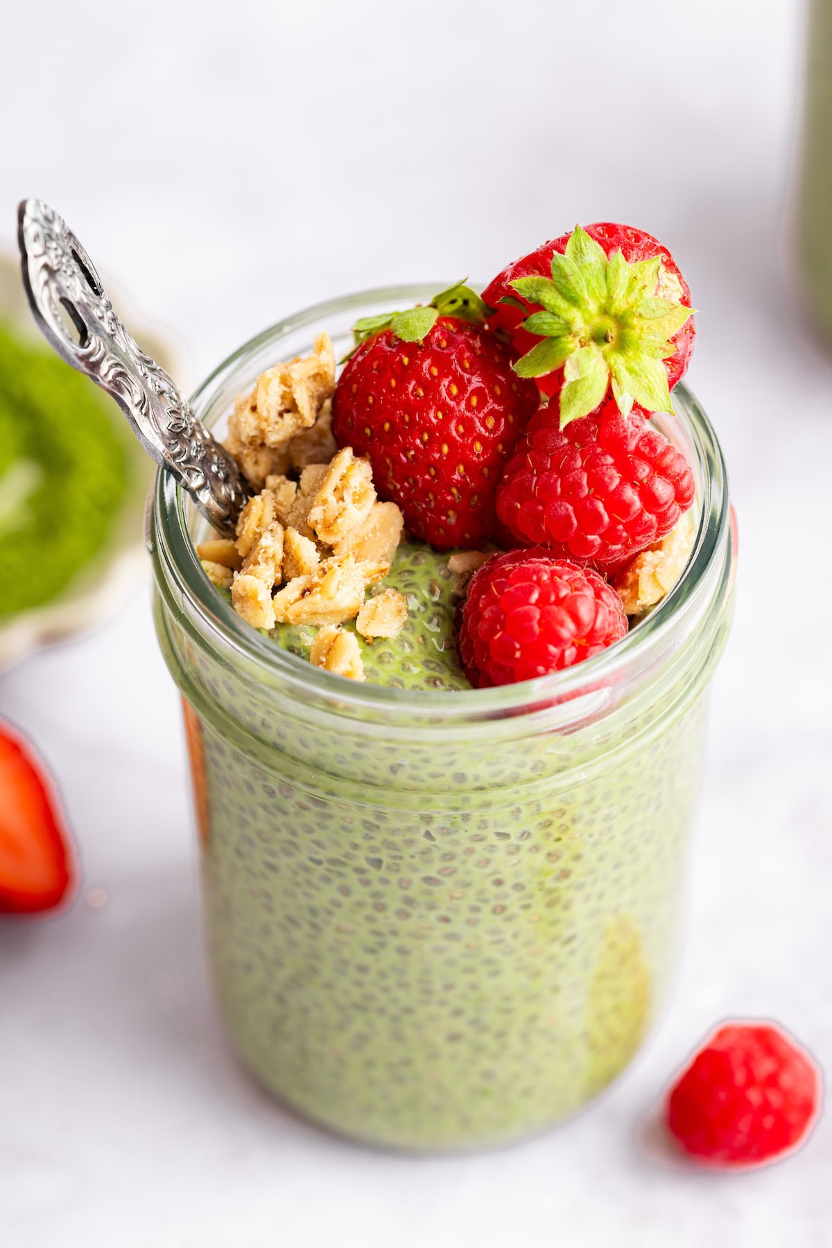 jar of matcha chia pudding Single jar of matcha chia pudding topped with strawberries and granola ready to eat.