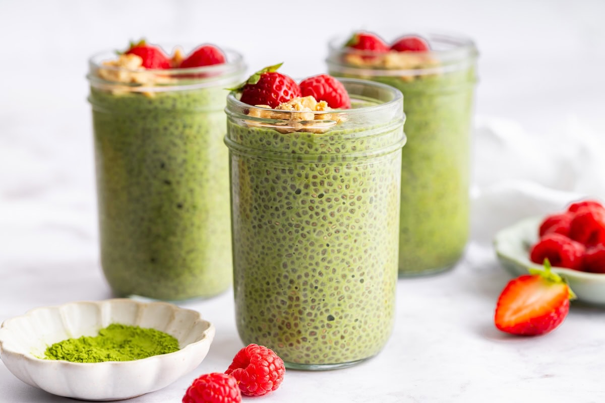Matcha Chia Pudding Matcha chia pudding in glass jars with strawberries and crunchy toppings for meal prep.