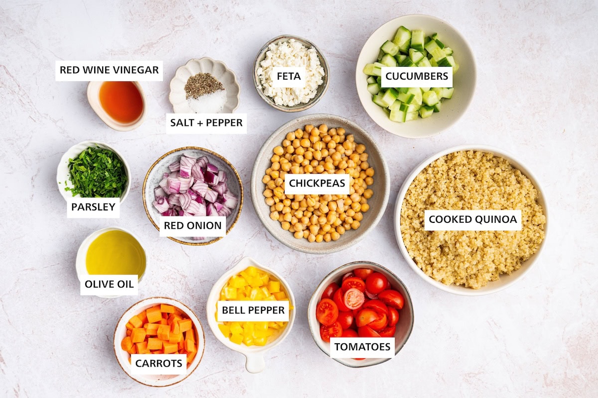 Quinoa Chickpea Salad ingredients: Cooked quinoa, cucumbers, chickpeas, tomatoes, feta, bell pepper, red onion, carrots, red wine vinegar, olive oil, parsley, pepper, salt.