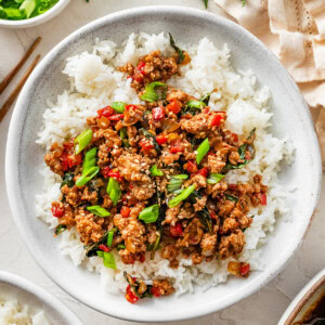 Thai basil chicken served over fluffy jasmine rice with fresh basil and green onions on top.