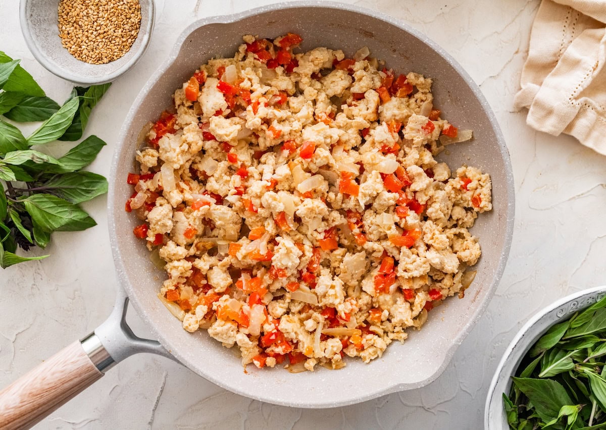 Ground chicken and diced bell pepper mixture Ground chicken and diced bell pepper mixture cooking in a skillet before adding sauce.