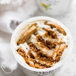 Crumbled cookies in a container of greek yogurt.