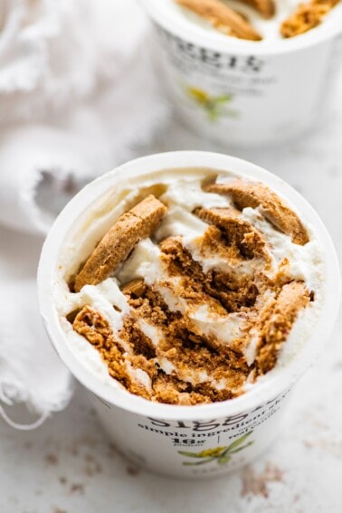 Crumbled cookies in a container of greek yogurt.