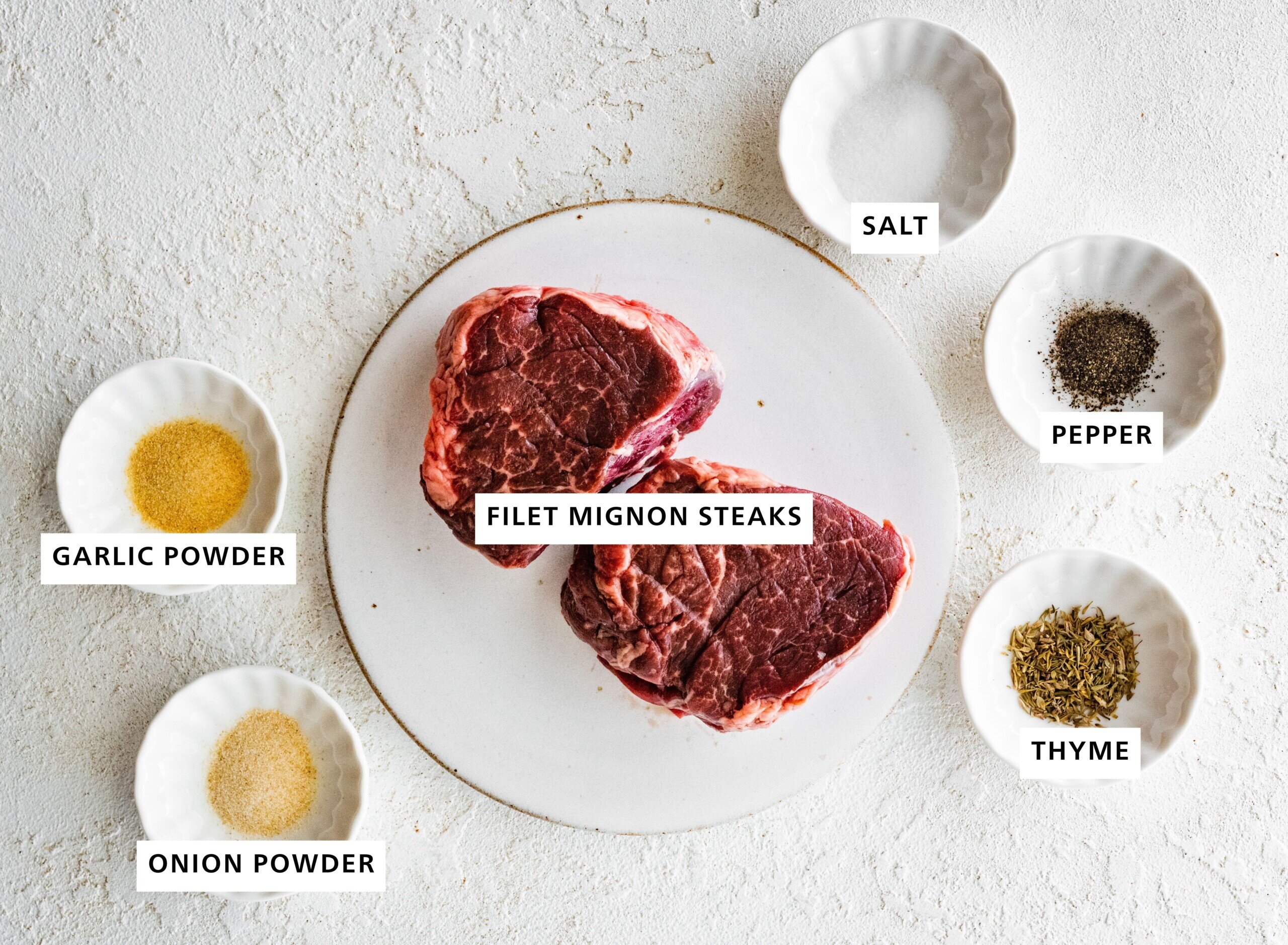 Ingredients measured out to make Air Fryer Filet Mignon: salt, pepper, thyme, filet mignon steaks, garlic powder and onion powder.