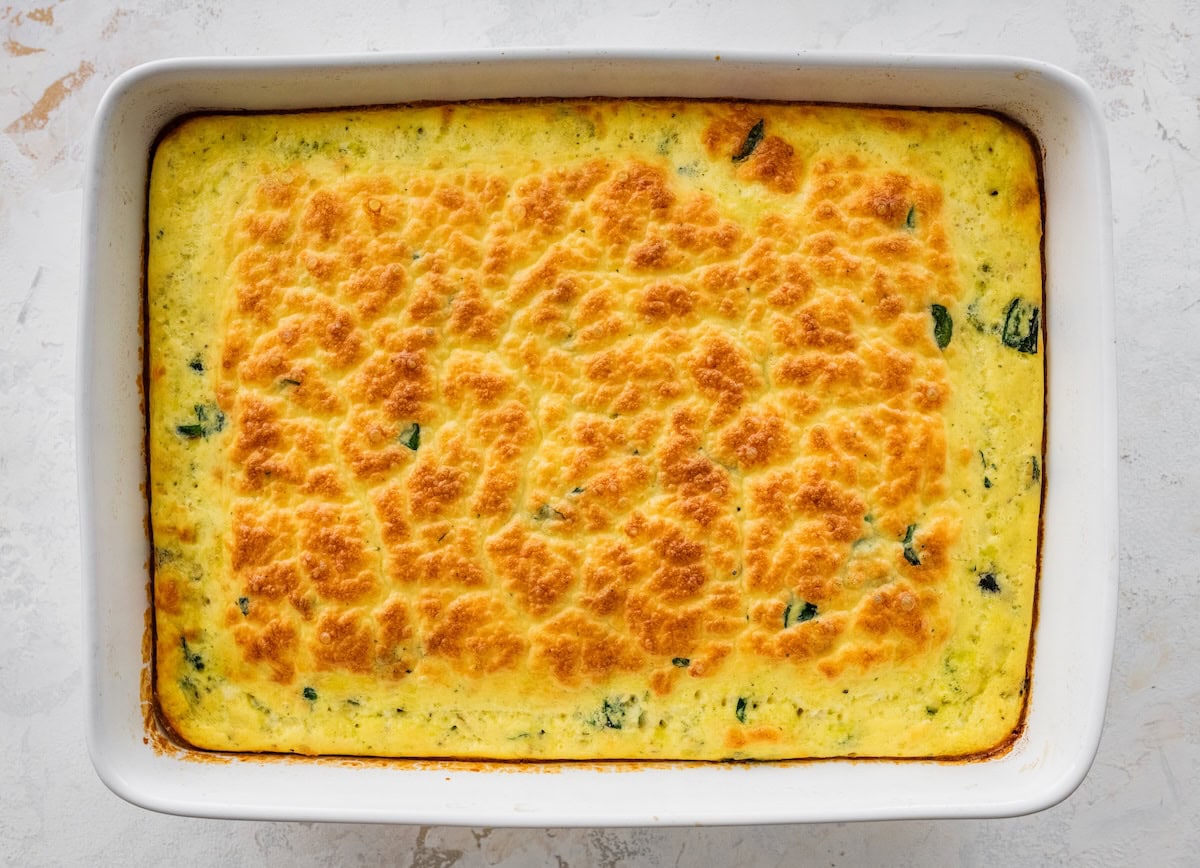 Baked cottage cheese egg casserole in dish with golden, cheesy top and spinach throughout.
