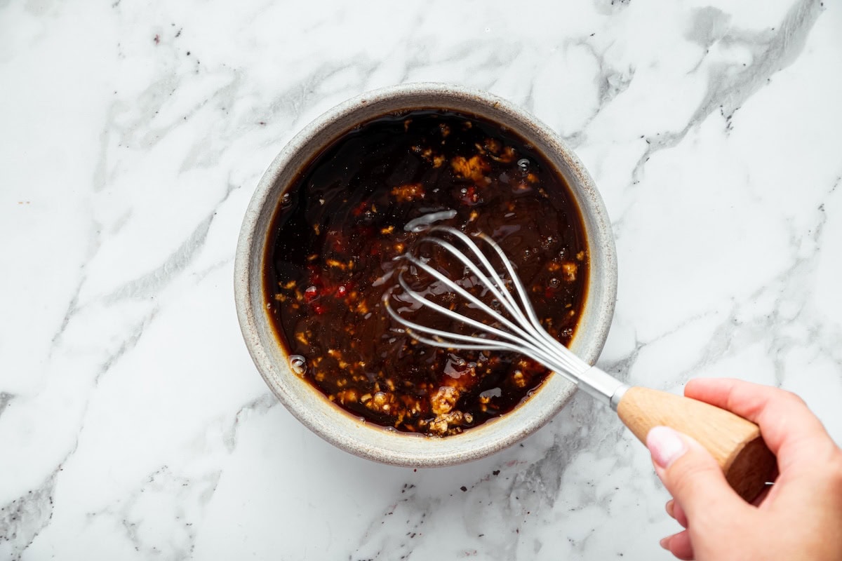 Soy-based glazed chicken sauce being whisked together in a small bowl before cooking.