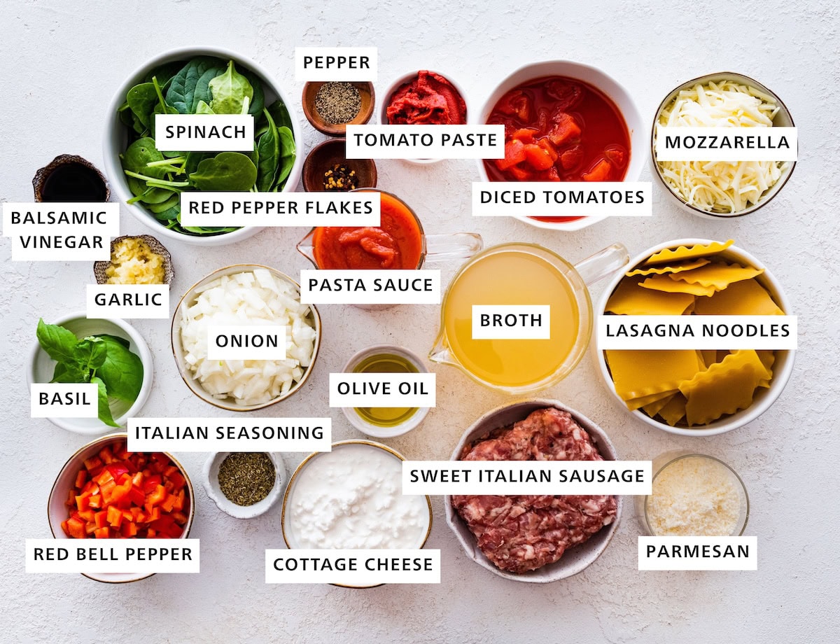 Ingredients measured out to make Lasagna Soup: mozzarella, lasagna noodles, parmesan, diced tomatoes, broth, sweet Italian sausage, tomato paste, pasta sauce, olive oil, cottage cheese, pepper, red pepper flakes, onion, baby spinach, Italian seasoning, garlic balsamic vinegar, basil and red bell pepper.