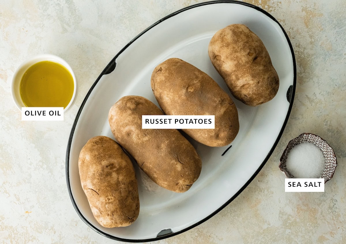 Ingredients measured out to make Oven Baked Potatoes: olive oil, russet potatoes and coarse kosher salt.