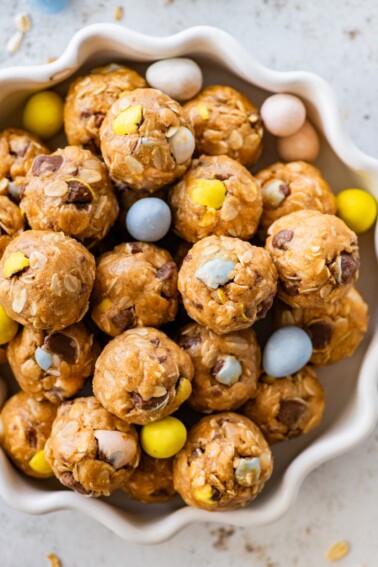 A bowl of protein balls with Cadbury Eggs around the balls in the bowl.