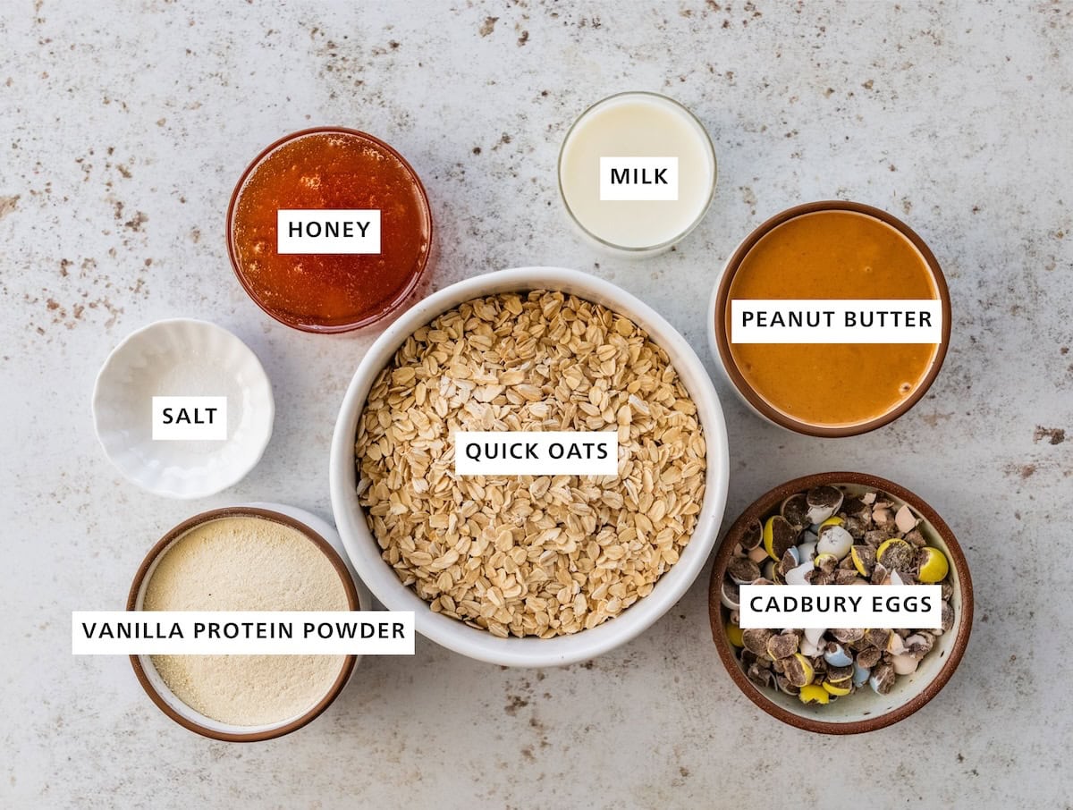 Ingredients measured out for Cadbury Egg protein balls: quick oats, vanilla protein powder, salt, cadbury eggs, peanut butter, milk, and honey.