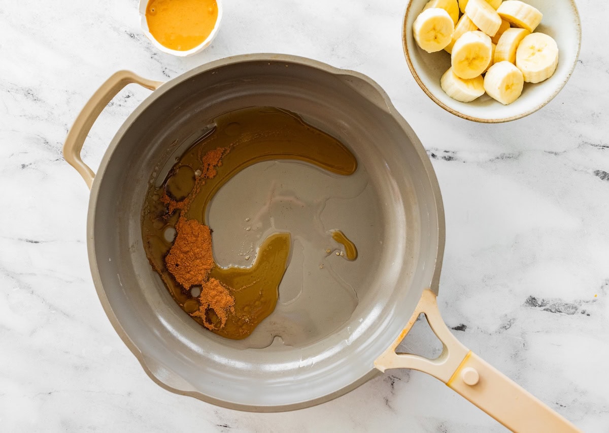 Cinnamon, and maple syrup being heated up in a pan.