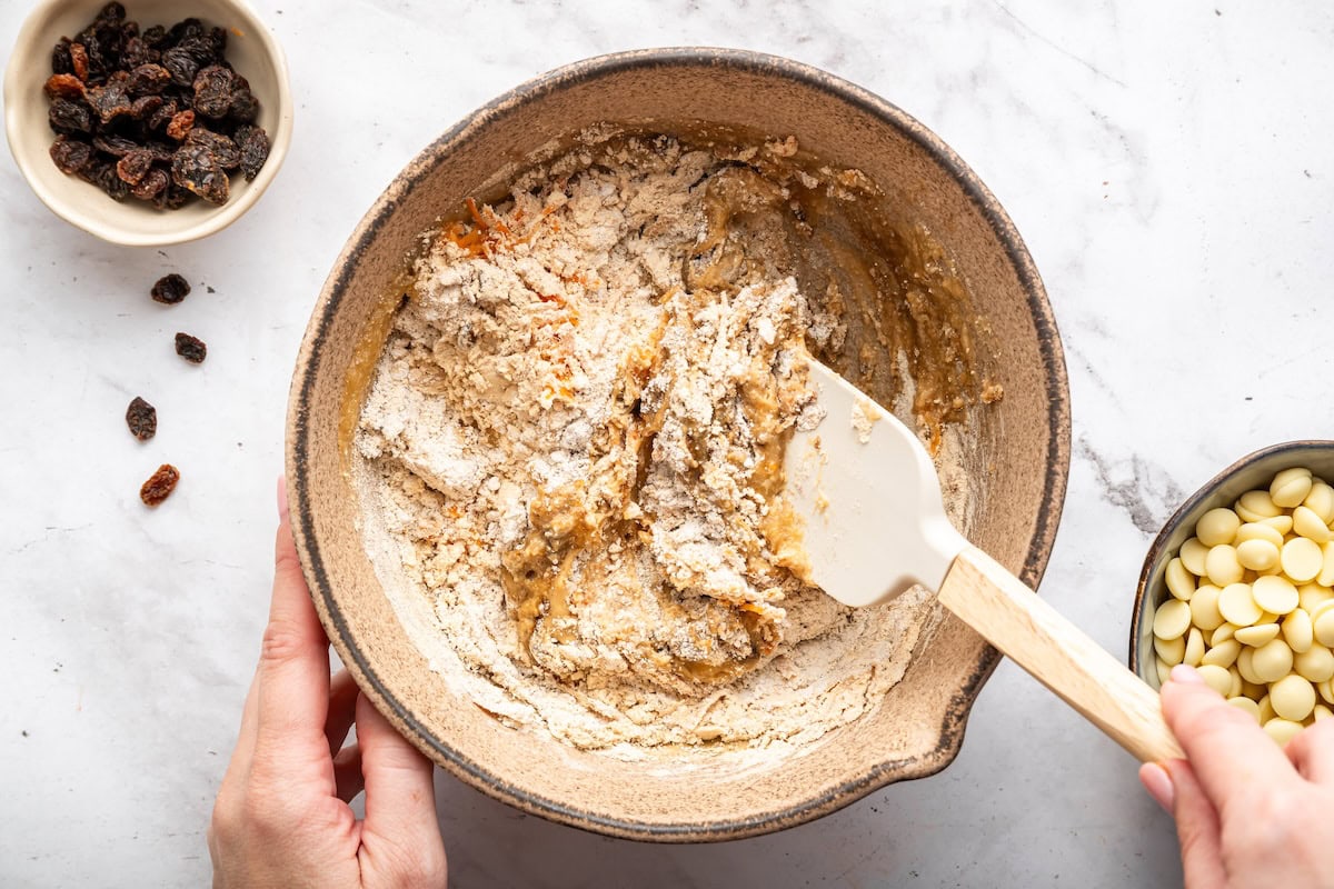 Mixing carrot cake protein ball dough in bowl with a spatula.