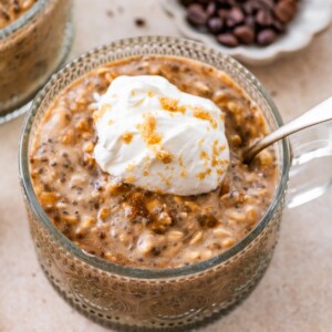 Brown sugar espresso overnight oats topped with whipped cream and brown sugar in glass bowl.