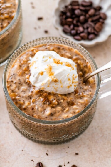 Brown sugar espresso overnight oats topped with whipped cream and brown sugar in glass bowl.