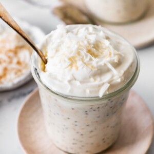 Creamy coconut overnight oats topped with whipped cream and lightly toasted shredded coconut.