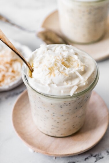 Creamy coconut overnight oats topped with whipped cream and lightly toasted shredded coconut.