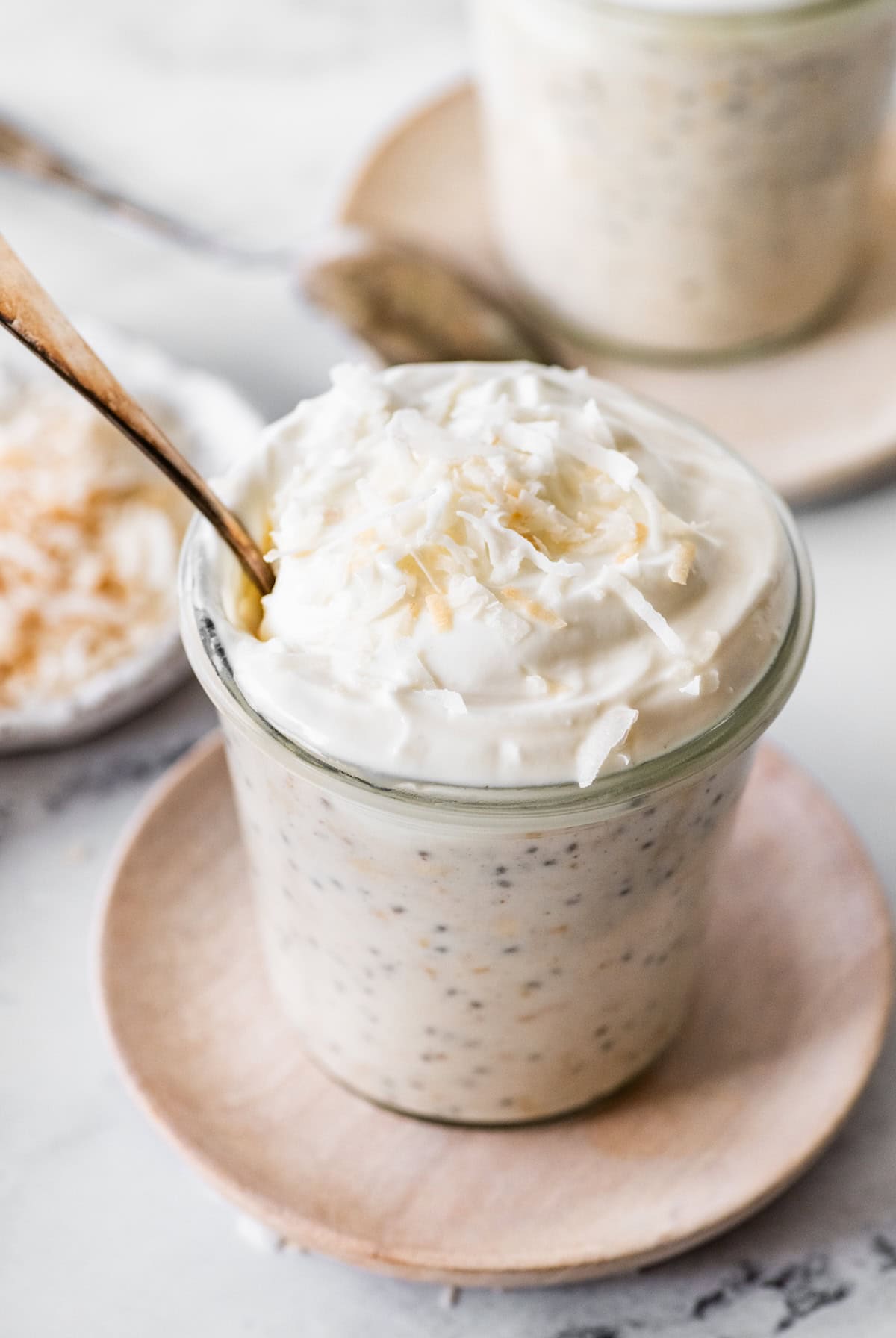 Creamy coconut overnight oats topped with whipped cream and lightly toasted shredded coconut.