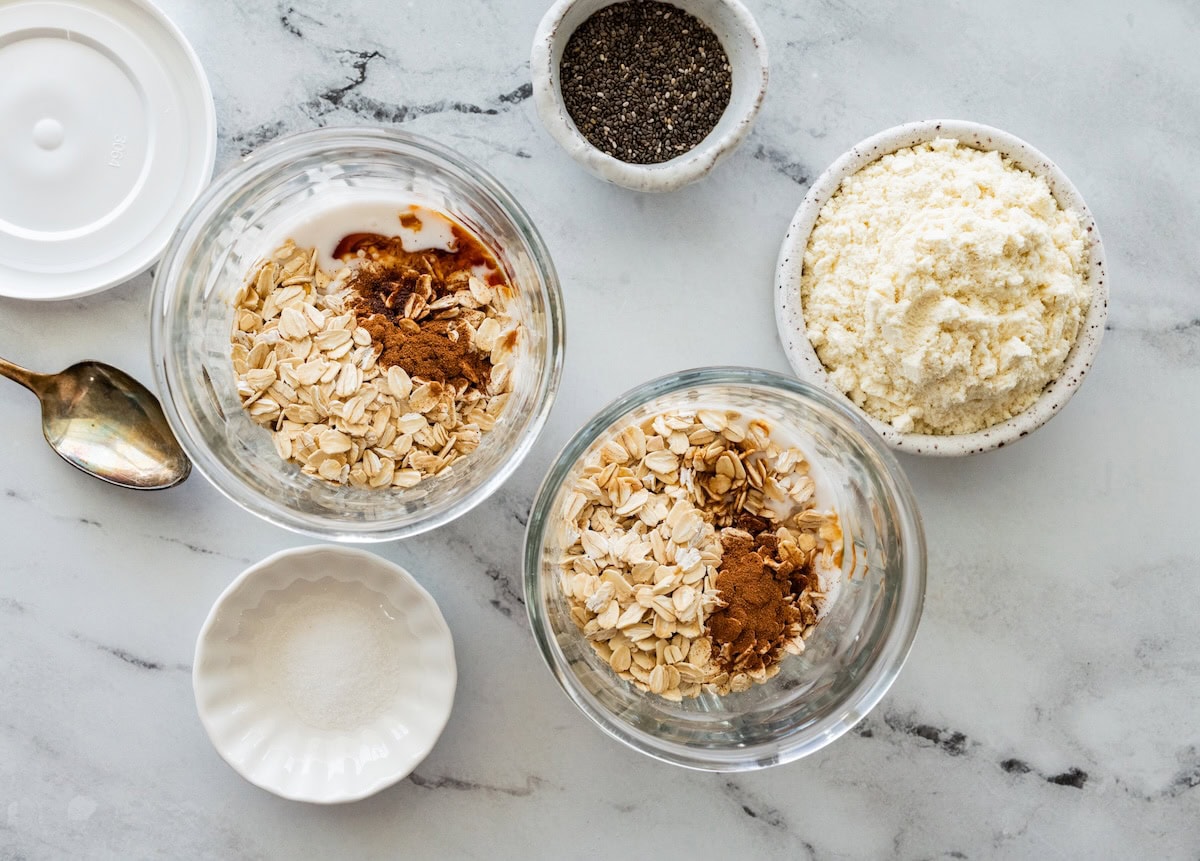 Ingredients for coconut overnight oats divided into two glass jars before milk has been added.