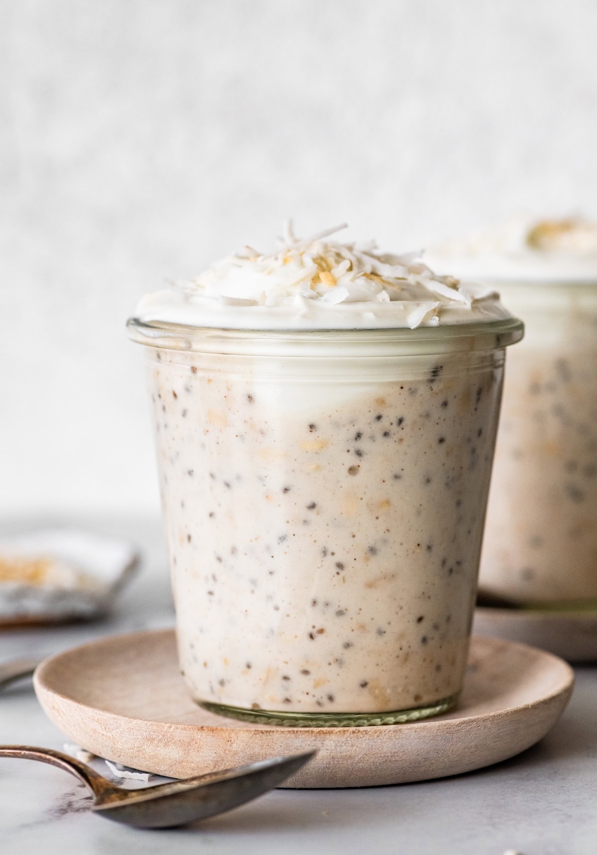 Creamy coconut cream pie overnight oats in a glass jar topped with whipped cream and toasted coconut.