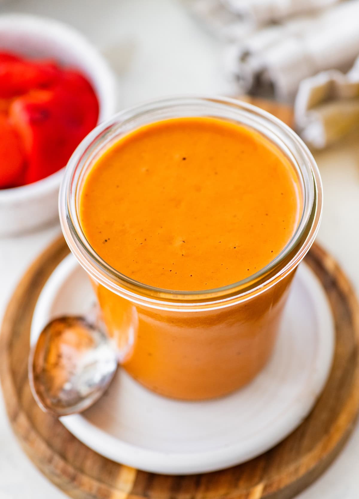 Creamy roasted red pepper dressing in a glass jar served alongside a spoon.