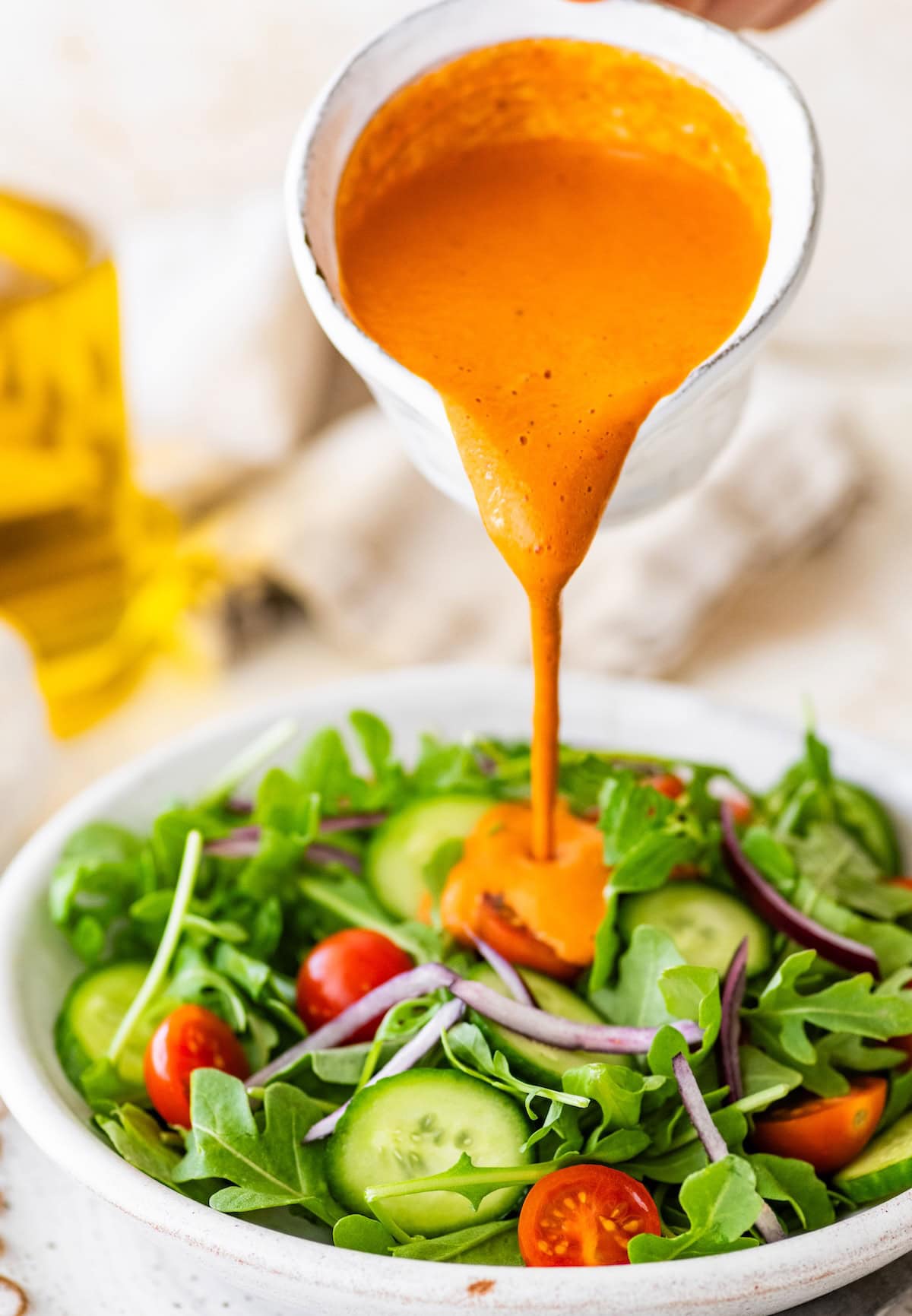 Creamy roasted red pepper dressing drizzled over fresh green salad with tomatoes, cucumbers and onions.