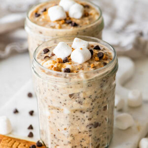 Two glass jars of s'mores overnight oats with marshmallows and chocolate chips.