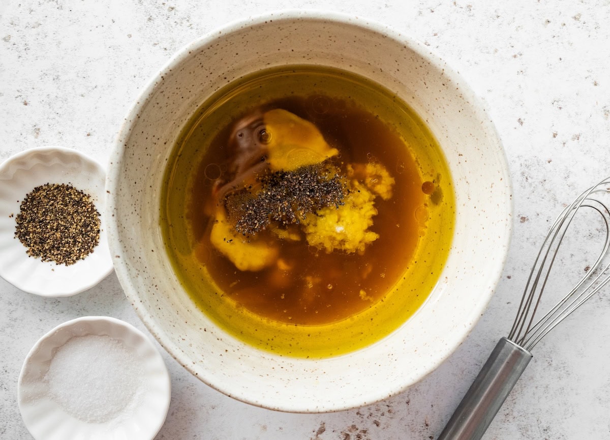 A mixing bowl with ingredients used for apple cider vinegar dressing before being whisked.