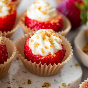 A cheesecake stuffed strawberry in a small cupcake liner topped with crushed graham crackers.