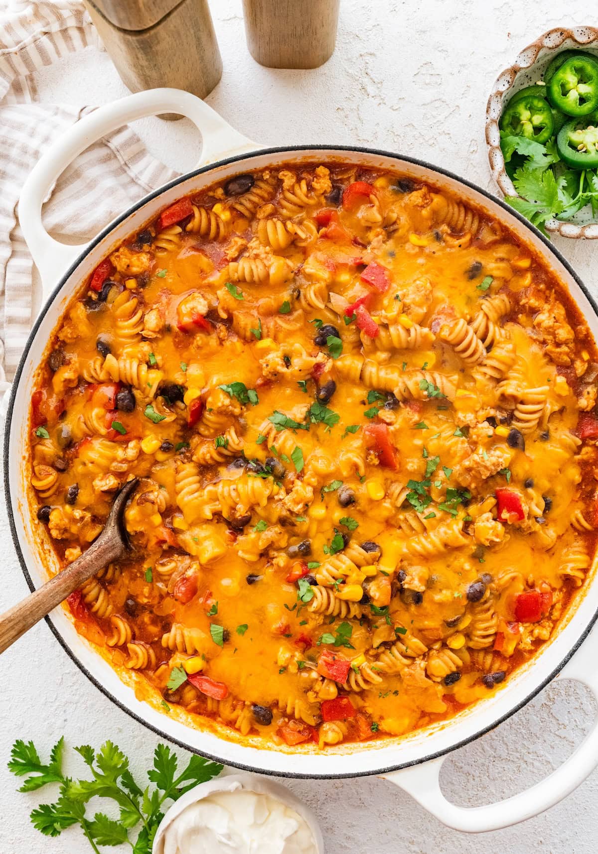 Enchilada pasta in a Dutch oven topped with melted cheese and fresh cilantro.
