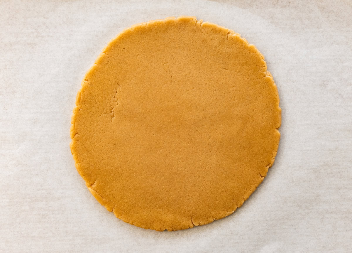Rolled-out sugar cookie dough pressed into a flat circle for fruit pizza crust.