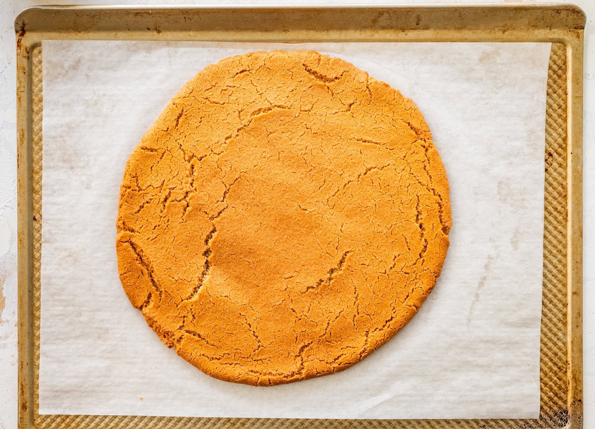 Baked sugar cookie crust on a parchment-lined baking sheet, lightly golden.