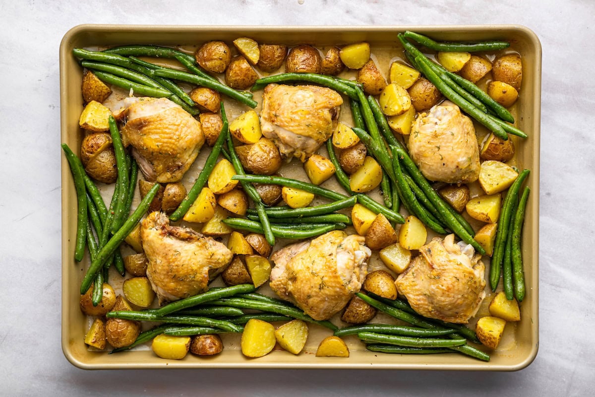Chicken thighs, potatoes, and green beans on a sheet pan.