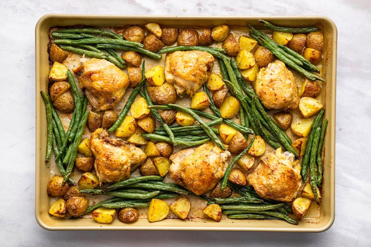 Roasted chicken thighs, potatoes, and green beans on a sheet pan.