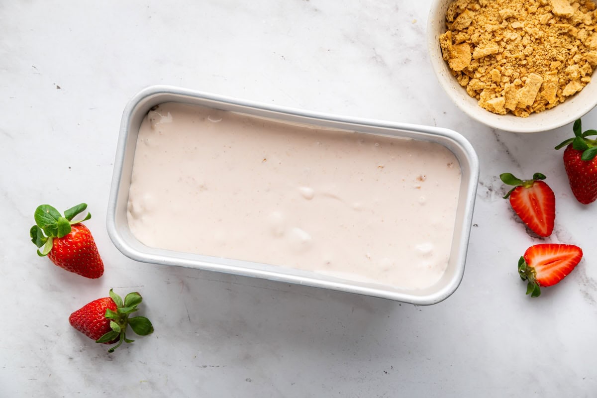 Strawberry cheesecake cottage cheese ice cream in an ice cream container.