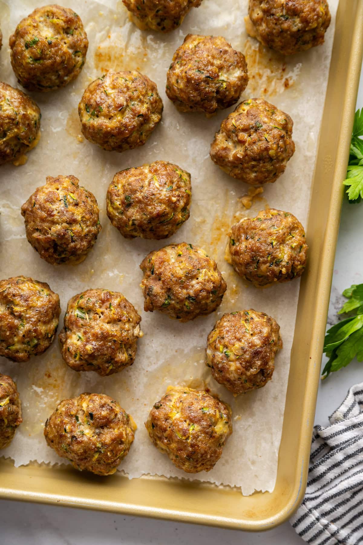 Baked zucchini meatballs on a baking tray.