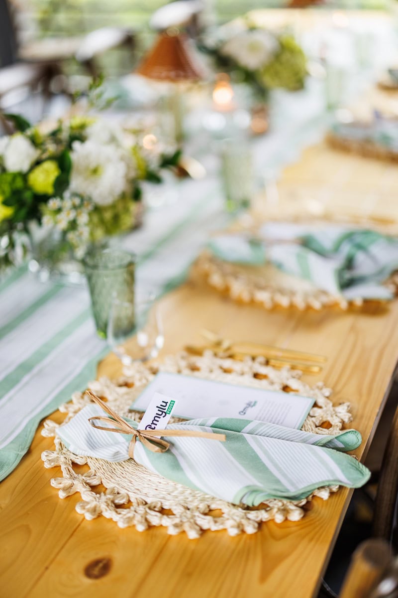 Fresh Air Retreat place setting with an Amylu Foods menu, striped napkin, and woven placemat.