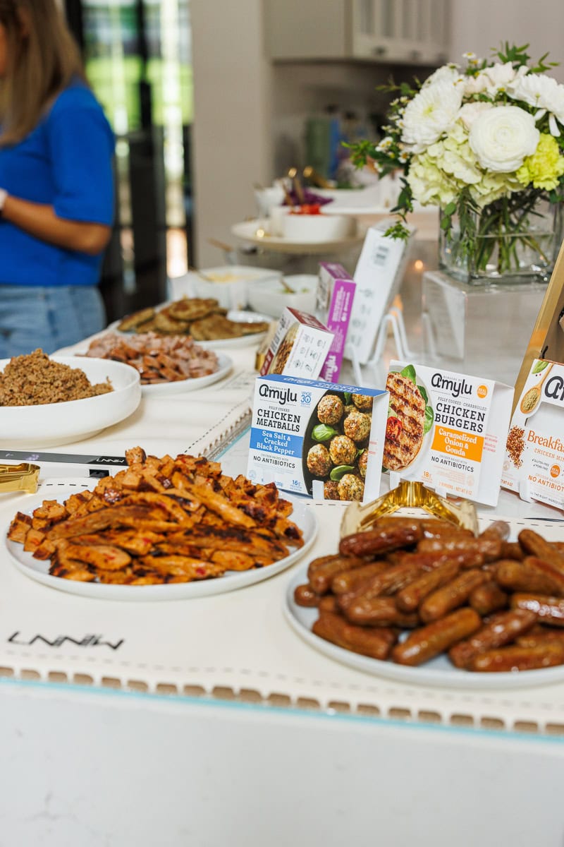Amylu Foods product tasting table with chicken sausages, chicken meatballs, and prepared sides.
