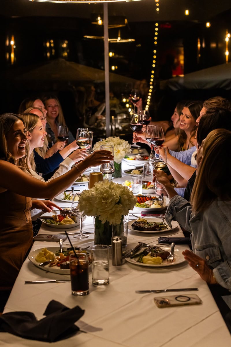Food bloggers toasting glasses around the table at a Fresh Air Retreat dinner.