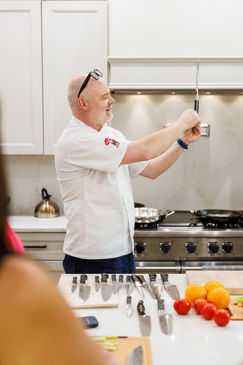 Chef demonstrating proper knife technique during a Fresh Air Retreat cooking session.